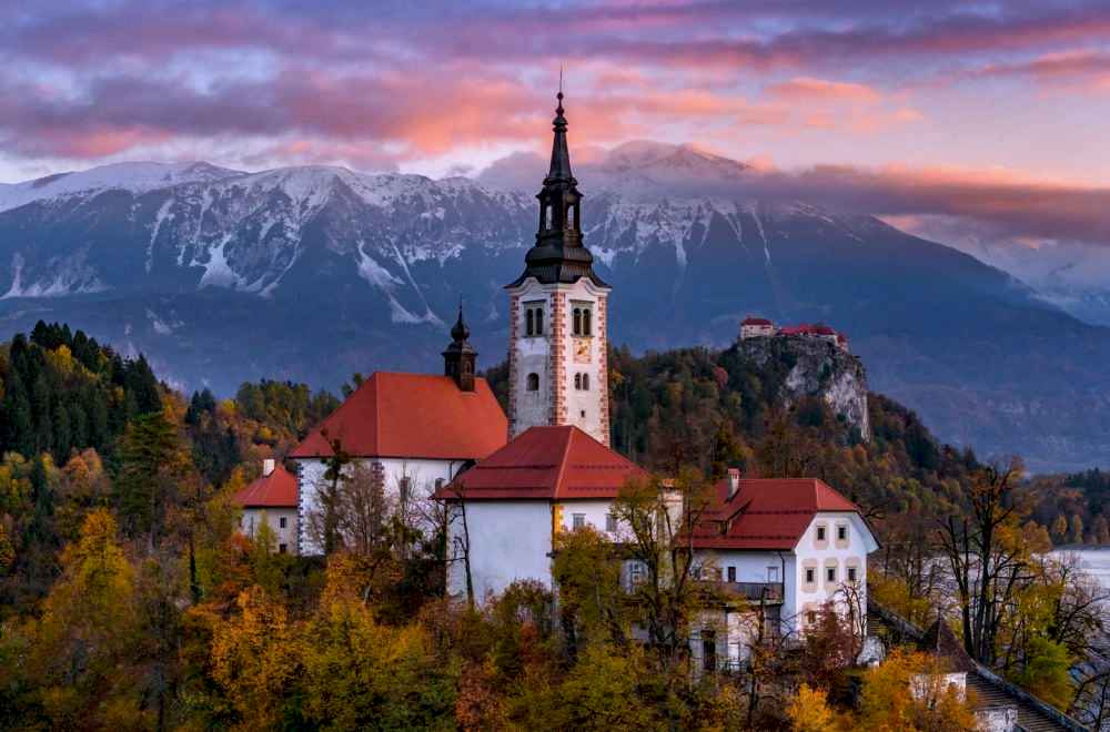 Church on Lake Bled surrounded by autumn foliage at sunrise, Slovenia