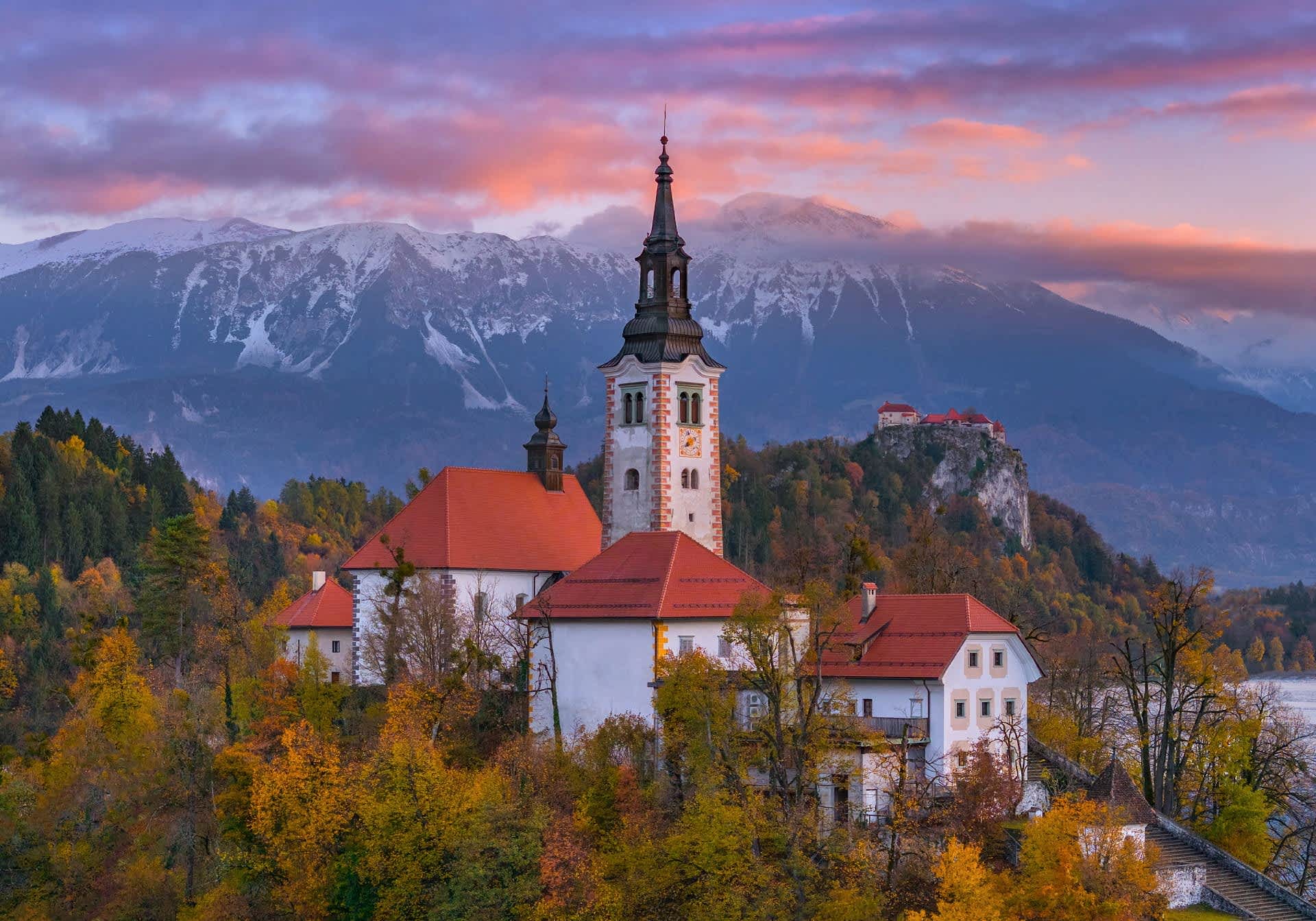 Church on Lake Bled surrounded by autumn foliage at sunrise, Slovenia