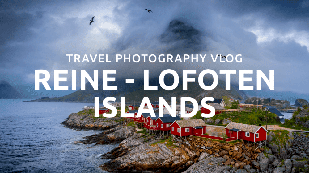 Red fishing cabins along rocky shoreline in Reine, Lofoten Islands, Norway