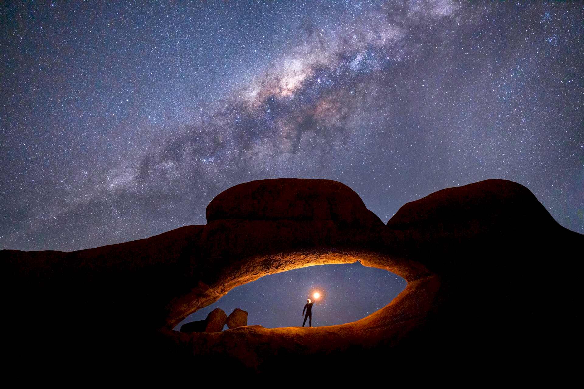Milky Way arch with a person holding a light, Spitzkoppe, Namibia